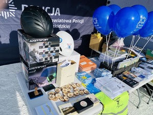 stoisko policji z nagrodami i ulotkami profilaktycznymi oraz niebieskimi balonami policji w suchej
