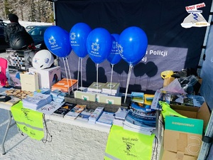 stoisko policji z nagrodami i ulotkami profilaktycznymi oraz niebieskimi balonami policji