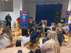 rodzice siedzący na sali audio wizualnej podczas prezentacji przedstawianej przez policjanta