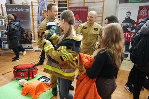 młodzież przy stoisku państwowej straży pożarnej przymierza mundury przy strażakach