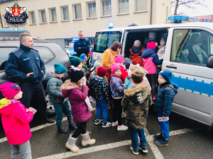 duże grono dzieci wsiadające do policyjnego furgonu