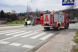 skręcający na skrzyżowaniu beczkowóz straży pożarnej i stojący na tym skrzyżowaniu policjant