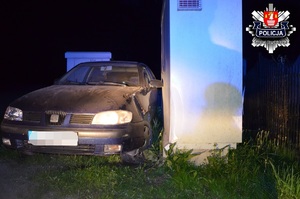 niebieski samochód marki seat z uszkodzonym bokiem stojący przy uszkodzonej białej skrzynce telekomunikacyjnej