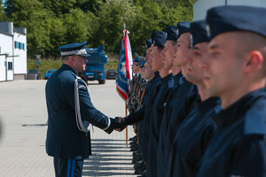 Komendant Wojewódzki Policji ściska rękę nowo przyjętemu policjantowi stojącemu w szeregu ze składającymi przysięgę policjantom