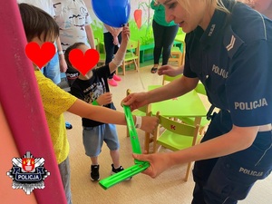 policjantka zakłada na rękę chłopca odblask na tle drugiego trzymającego balon z napisem KPP w Suchej Beskidzkiej
