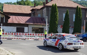 policjanci kierujący ruchem na skrzyżowaniu i jadący oklejony biały samochód rajdowy