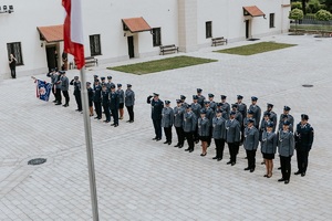 Flaga Polski na tle stojących policjantów na dziedzińcu suskiego zamku