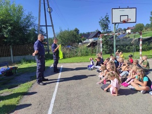 policjanci podczas spotkania z pierwszoklasistami w szkole w Kurowie prezentują kamizelkę odblaskową i tłumaczą dzieciom jak waznym jest elementem na drodze