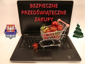 Zdjęcie przedstawiające logo komendy Wojewódzkiej Policji w Krakowie znajdujące się po lewej środkowej części zdjęcia a po drugiej stronie mała choinkę a na środku duży otwarty laptop, na którego klawiaturze znajduję się metalowy koszyk pełny zapakowanych prezentów. Na ekranie tego laptopa czerwoną czcionką znajduję się napis czerwonymi drukowanymi literami o treści bezpieczne przedświąteczne zakupy.