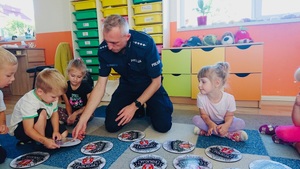 policjant z chłopczykiem odsłania krążek menory z niebezpieczną zabawą gry w piłkę na drodze