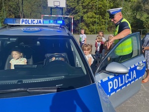 dzieci oglądające radiowóz od środka w obecności policjanta z ruchu drogowego