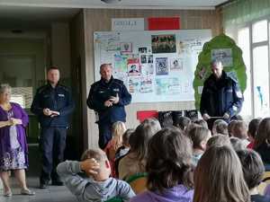 policjanci stojący przed dziećmi na zajęciach w szkole