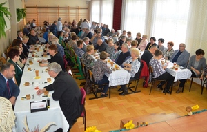 seniorzy siedzący przy stołach przed rozpoczęciem uroczystości Dnia Seniora