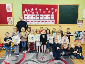 dzieci z policjantem pozują do zdjęć z odblaskami