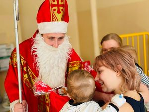 Mikołaj rozmawiający z mamą trzymającą na rękach malutkiego chłopczyka