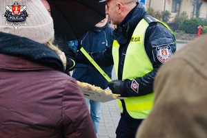 policjant ruchu drogowego wręczający opaski odblaskowe