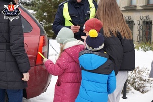 dzieci odbierają od policjanta opaski odblaskowe