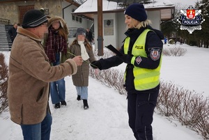 mężczyzna odbiera od policjantki opaskę odblaskową